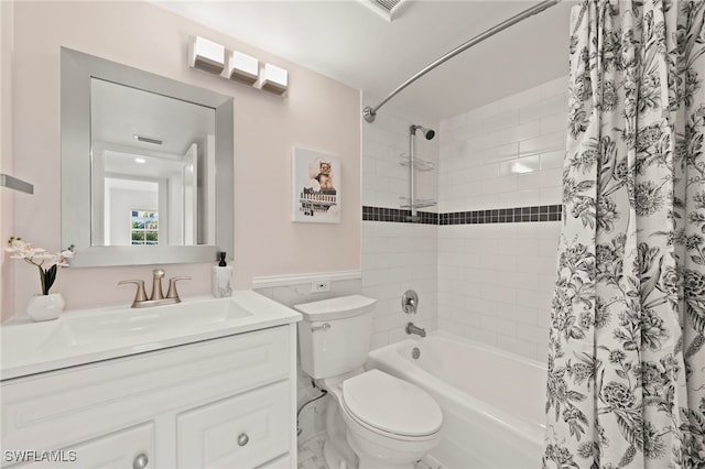 bathroom featuring toilet, tile walls, vanity, wainscoting, and shower / bathtub combination with curtain