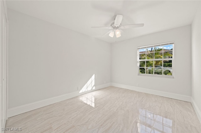 spare room featuring a ceiling fan and baseboards