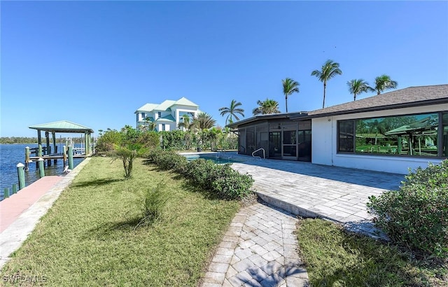 view of yard featuring a water view, a boat dock, and a sunroom