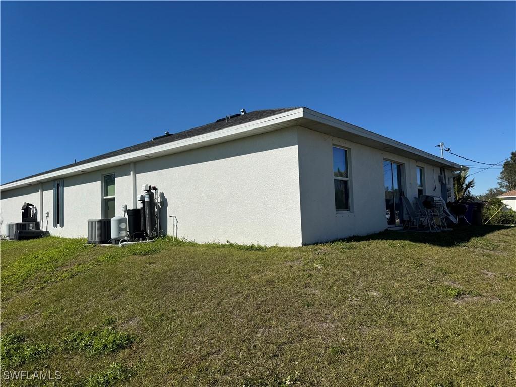 view of side of home with central air condition unit and a lawn