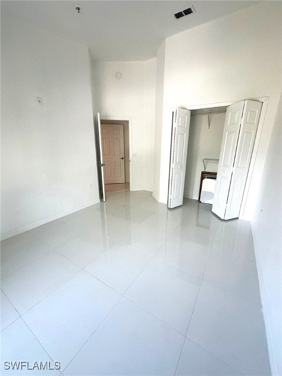 empty room with a towering ceiling and light tile patterned flooring