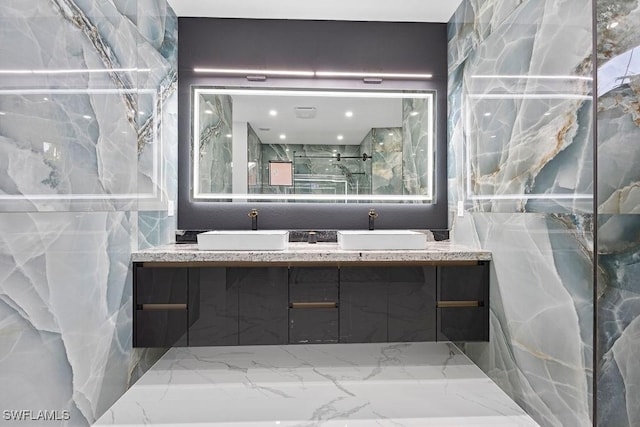 bathroom with vanity, a shower with door, and tile walls