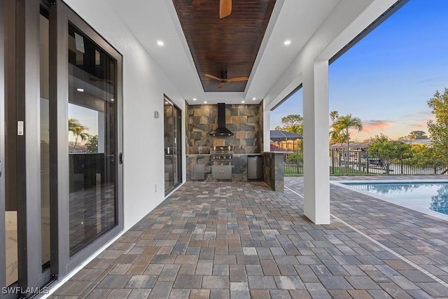 patio terrace at dusk with area for grilling, a fenced in pool, and grilling area