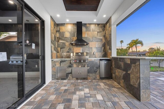 patio terrace at dusk with area for grilling, a grill, and sink