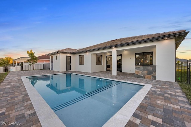 pool at dusk with a patio area