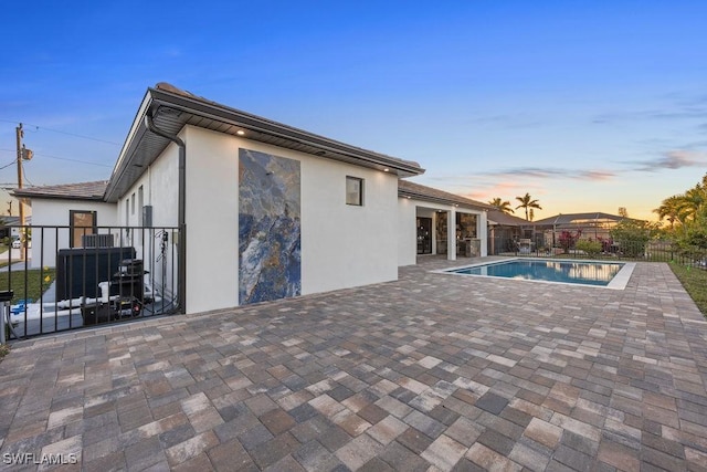 pool at dusk with central AC unit and a patio