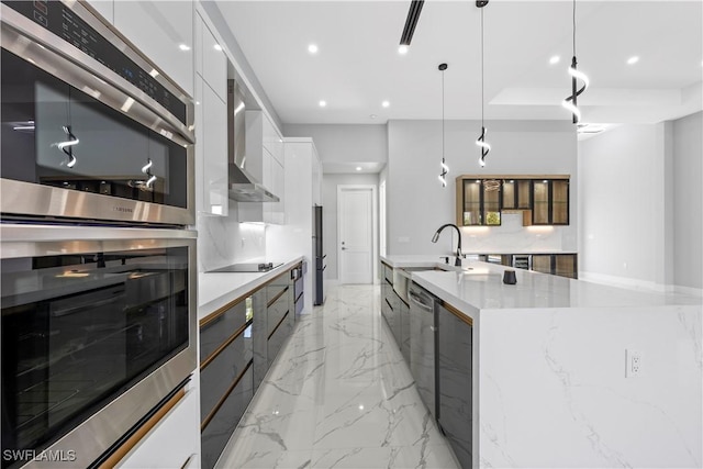 kitchen with appliances with stainless steel finishes, pendant lighting, white cabinetry, sink, and a spacious island