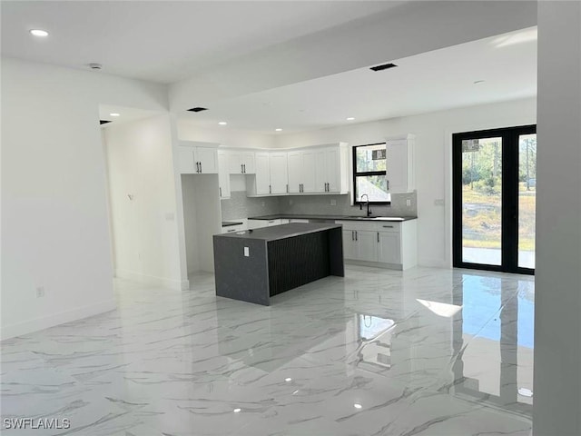 kitchen featuring backsplash, sink, a kitchen island, and white cabinets