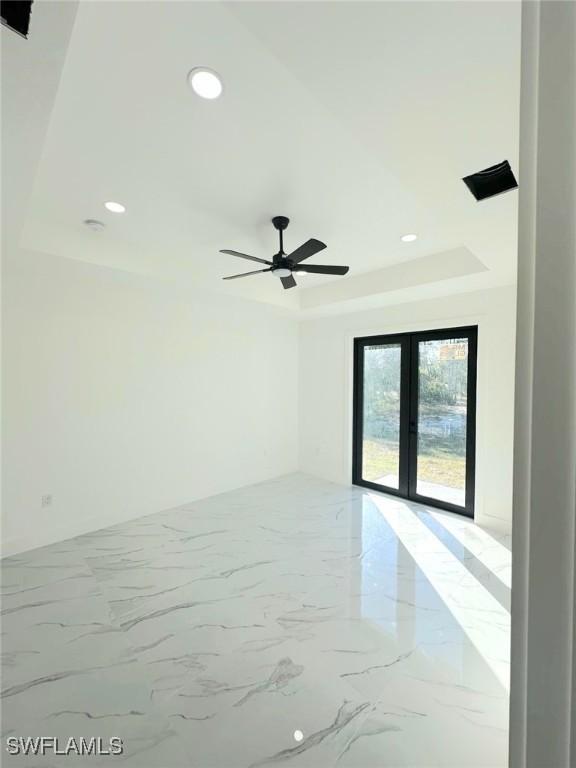 empty room featuring a raised ceiling and french doors