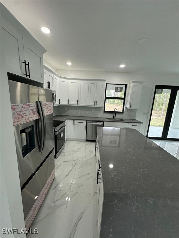 kitchen featuring white cabinetry, sink, dark stone counters, and appliances with stainless steel finishes