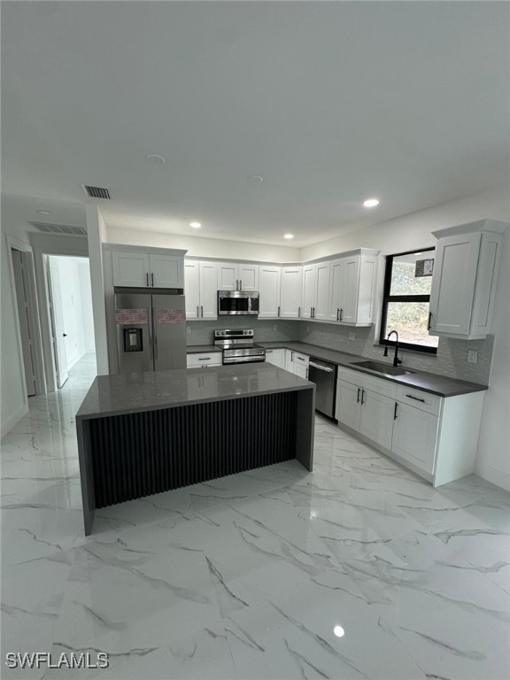 kitchen featuring sink, a center island, white cabinets, and appliances with stainless steel finishes