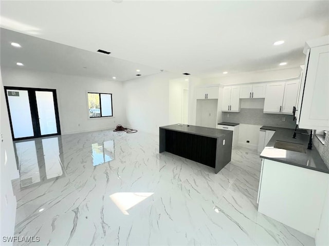 kitchen with white cabinetry, tasteful backsplash, sink, and a kitchen island