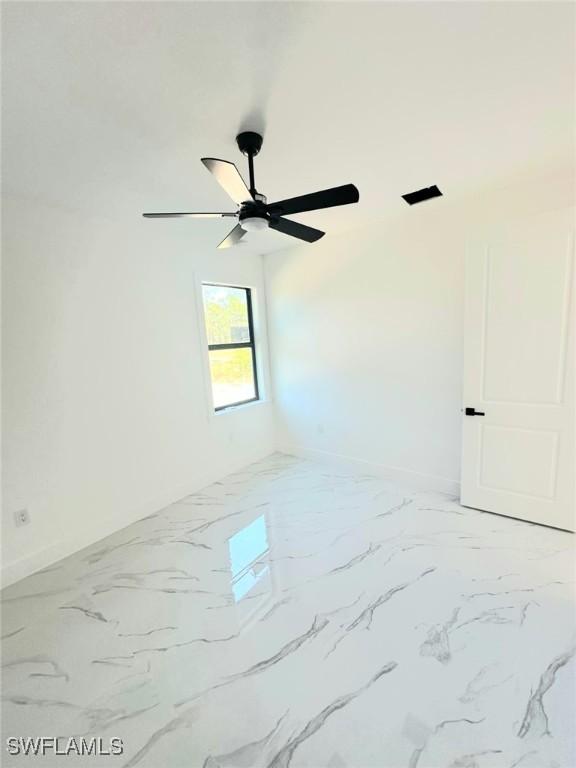 unfurnished room featuring baseboards, marble finish floor, and ceiling fan