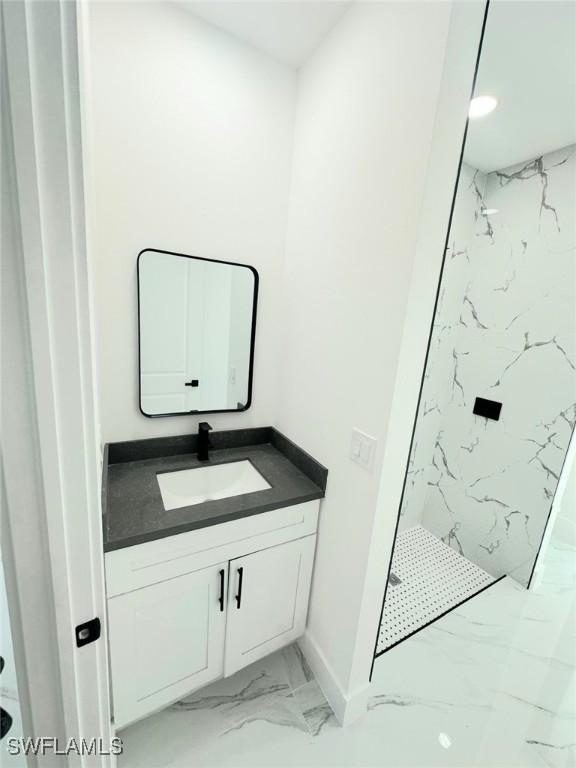 bathroom with a marble finish shower, baseboards, marble finish floor, and vanity