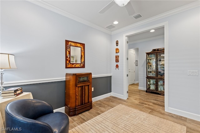 living area featuring crown molding, ceiling fan, and light wood-type flooring