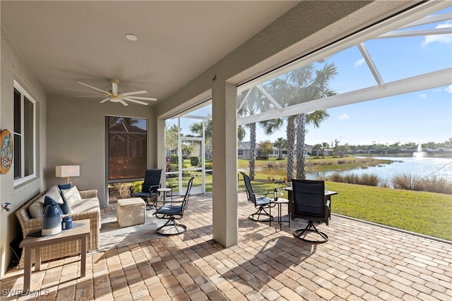 view of patio with ceiling fan, an outdoor hangout area, glass enclosure, and a water view