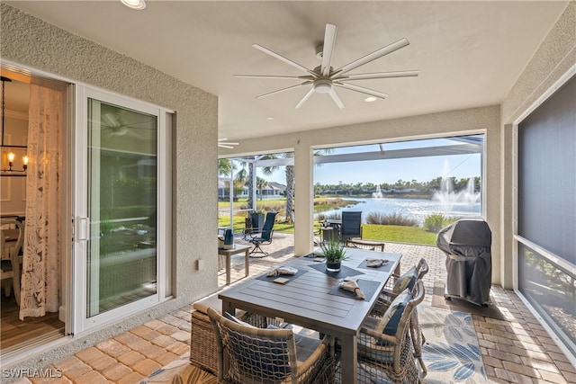 sunroom / solarium featuring a water view and ceiling fan