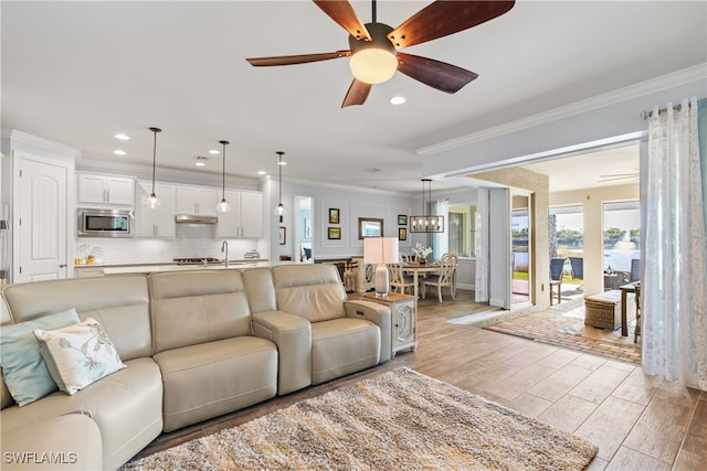 living room featuring crown molding, ceiling fan, and light wood-type flooring