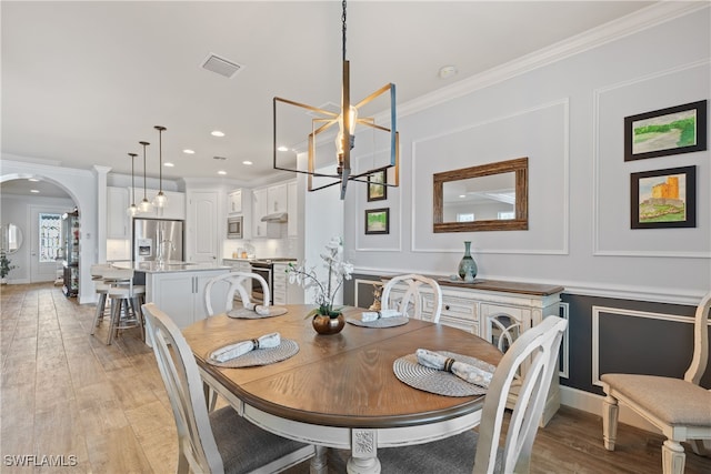 dining space featuring ornamental molding, a chandelier, and light hardwood / wood-style floors