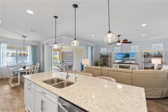 kitchen with sink, crown molding, light stone counters, pendant lighting, and white cabinets