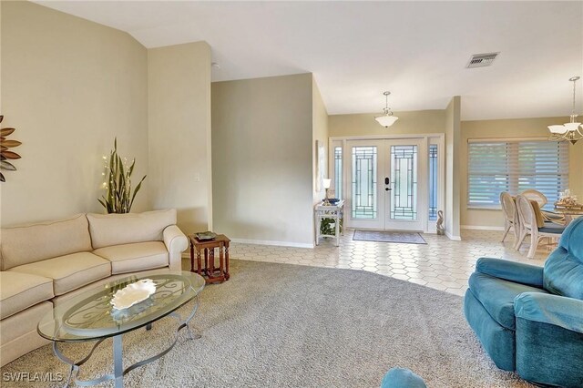 living room featuring french doors, light tile patterned floors, light colored carpet, visible vents, and a chandelier