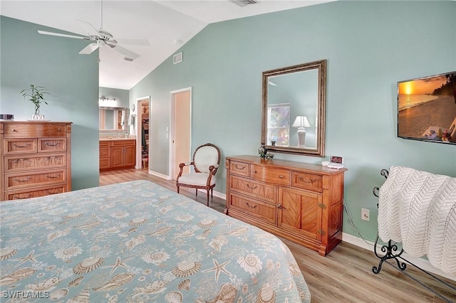 bedroom featuring visible vents, baseboards, vaulted ceiling, light wood finished floors, and ensuite bath