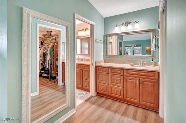 full bathroom featuring a spacious closet, vanity, and wood finished floors