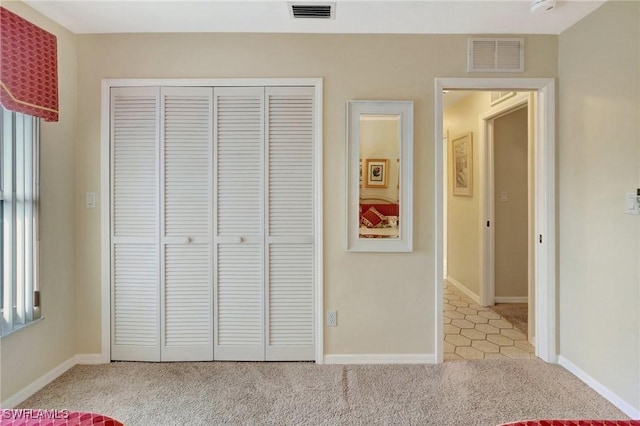 unfurnished bedroom featuring a closet, visible vents, light carpet, and multiple windows