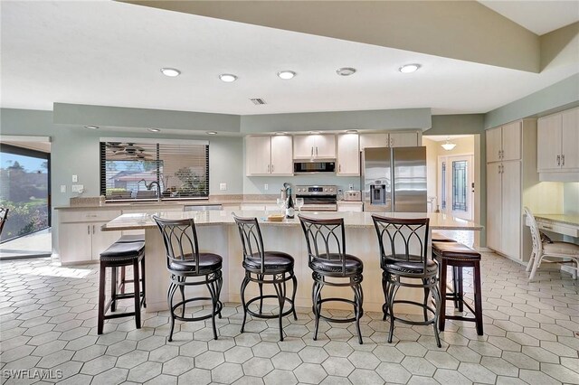 kitchen featuring light stone countertops, a kitchen breakfast bar, stainless steel appliances, and a center island