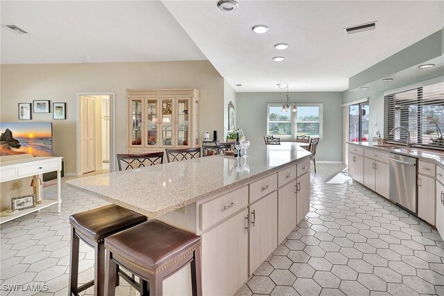 kitchen with hanging light fixtures, a kitchen bar, visible vents, and stainless steel dishwasher