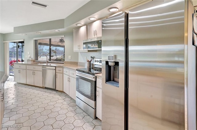 kitchen featuring light countertops, visible vents, appliances with stainless steel finishes, white cabinetry, and a sink