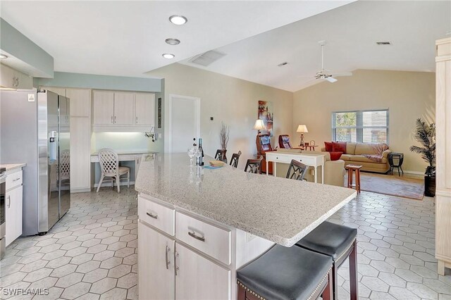 kitchen featuring stainless steel appliances, open floor plan, visible vents, and a kitchen bar