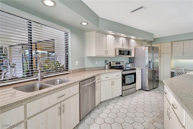 kitchen featuring visible vents, appliances with stainless steel finishes, light stone countertops, a sink, and recessed lighting