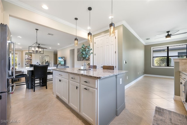 kitchen with stainless steel refrigerator, hanging light fixtures, light stone counters, white cabinets, and a kitchen island