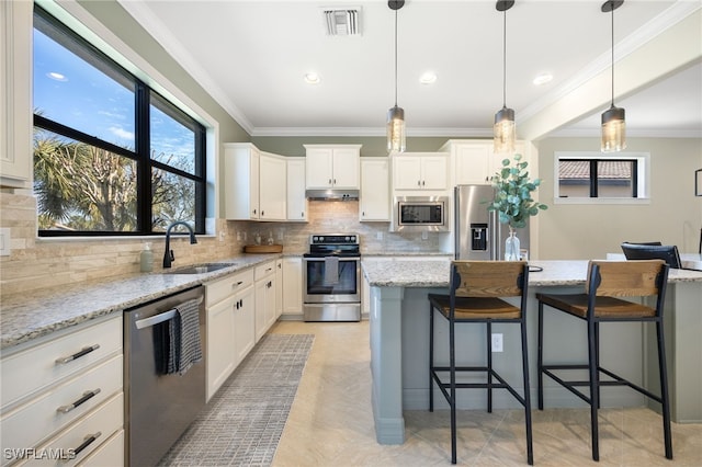 kitchen featuring sink, a center island, stainless steel appliances, light stone countertops, and white cabinets