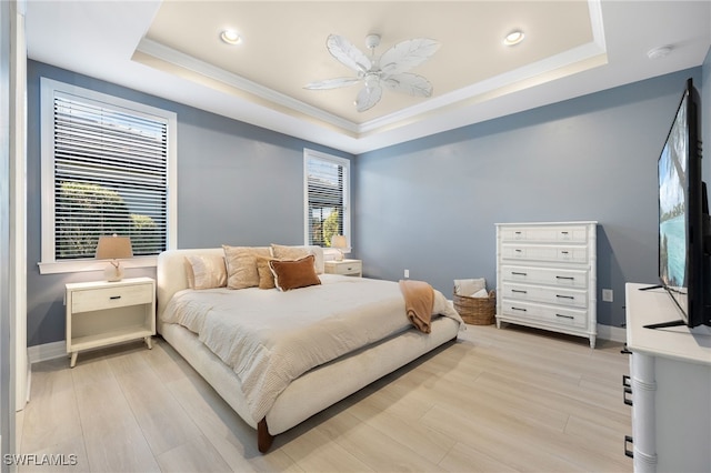 bedroom with ceiling fan, ornamental molding, a raised ceiling, and light hardwood / wood-style flooring