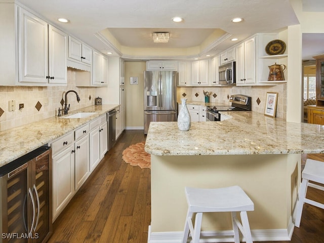 kitchen with beverage cooler, a sink, open shelves, stainless steel appliances, and a raised ceiling