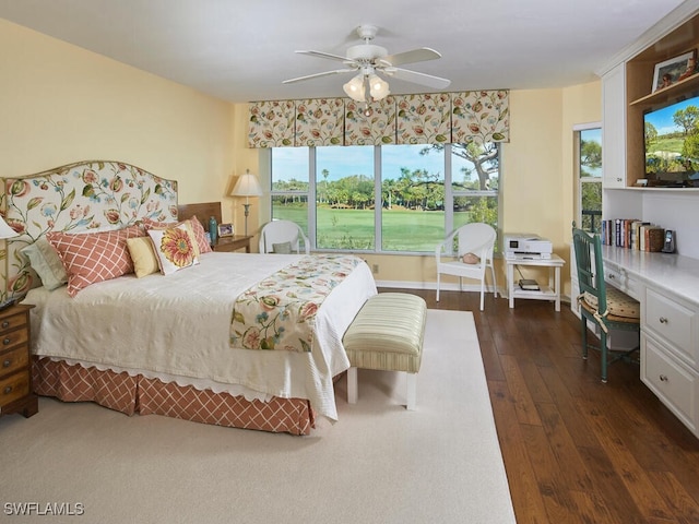 bedroom with dark wood-type flooring, ceiling fan, and built in desk