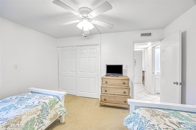 carpeted bedroom with a textured ceiling, ceiling fan, and a closet