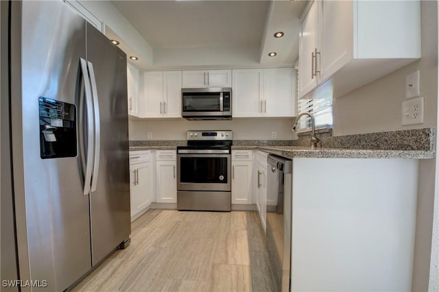 kitchen featuring sink, dark stone counters, white cabinets, and appliances with stainless steel finishes