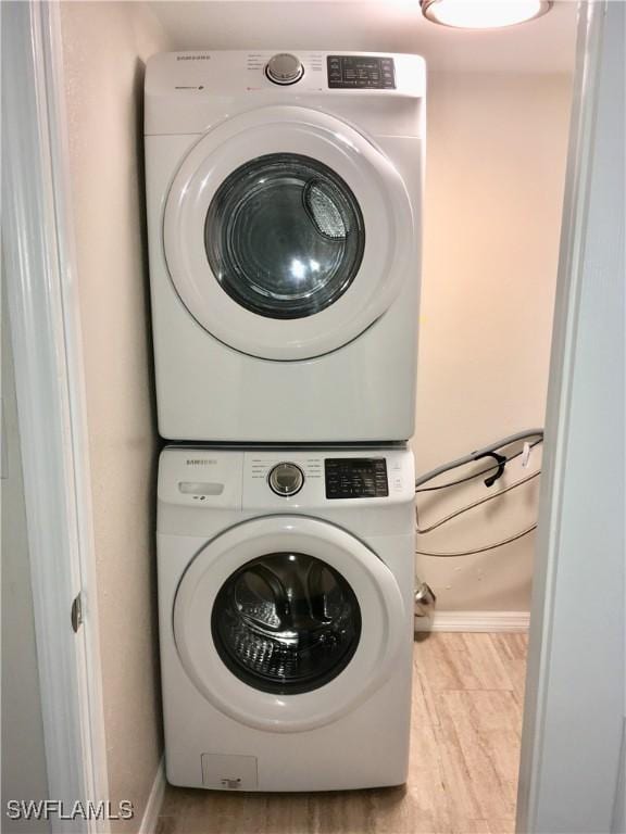 laundry room with stacked washing maching and dryer and light hardwood / wood-style floors