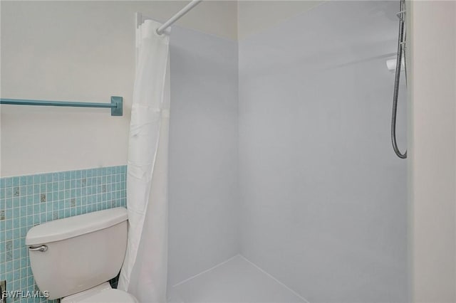 bathroom featuring toilet, a shower with shower curtain, and tile walls