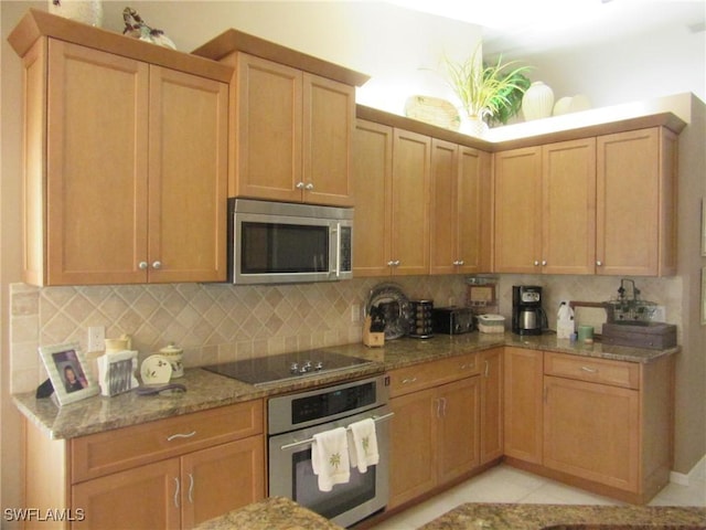 kitchen with tasteful backsplash, light tile patterned floors, light stone countertops, and appliances with stainless steel finishes