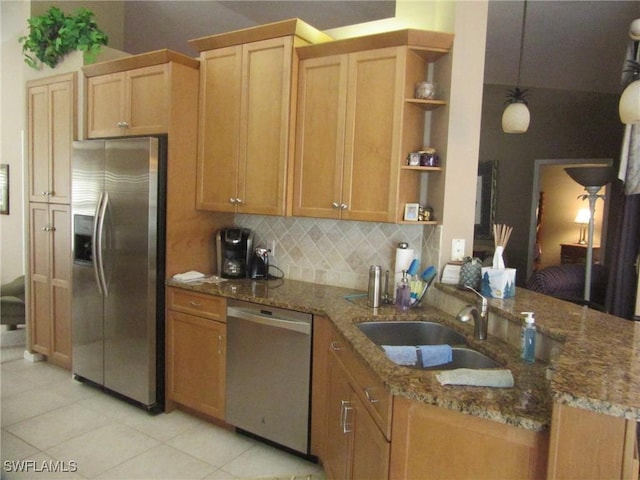 kitchen with pendant lighting, sink, appliances with stainless steel finishes, tasteful backsplash, and light stone counters