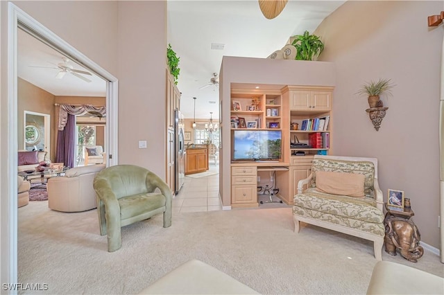 living area with light carpet, ceiling fan with notable chandelier, and built in desk