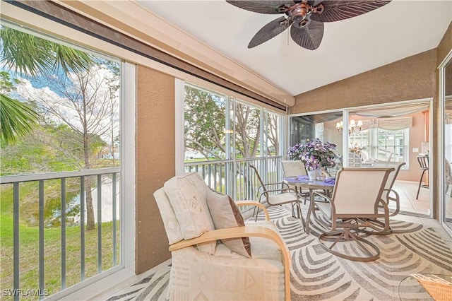 sunroom / solarium with ceiling fan with notable chandelier and vaulted ceiling