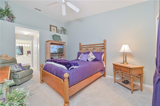 carpeted bedroom with ensuite bathroom and ceiling fan