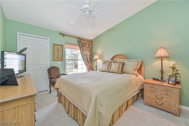 bedroom with vaulted ceiling, light carpet, ceiling fan, and a closet