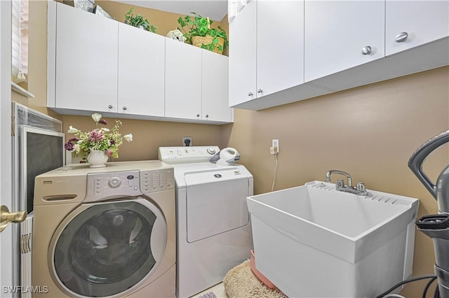 laundry room with cabinets, washer and clothes dryer, and sink