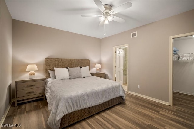 bedroom with a spacious closet, ceiling fan, dark wood-type flooring, ensuite bath, and a closet